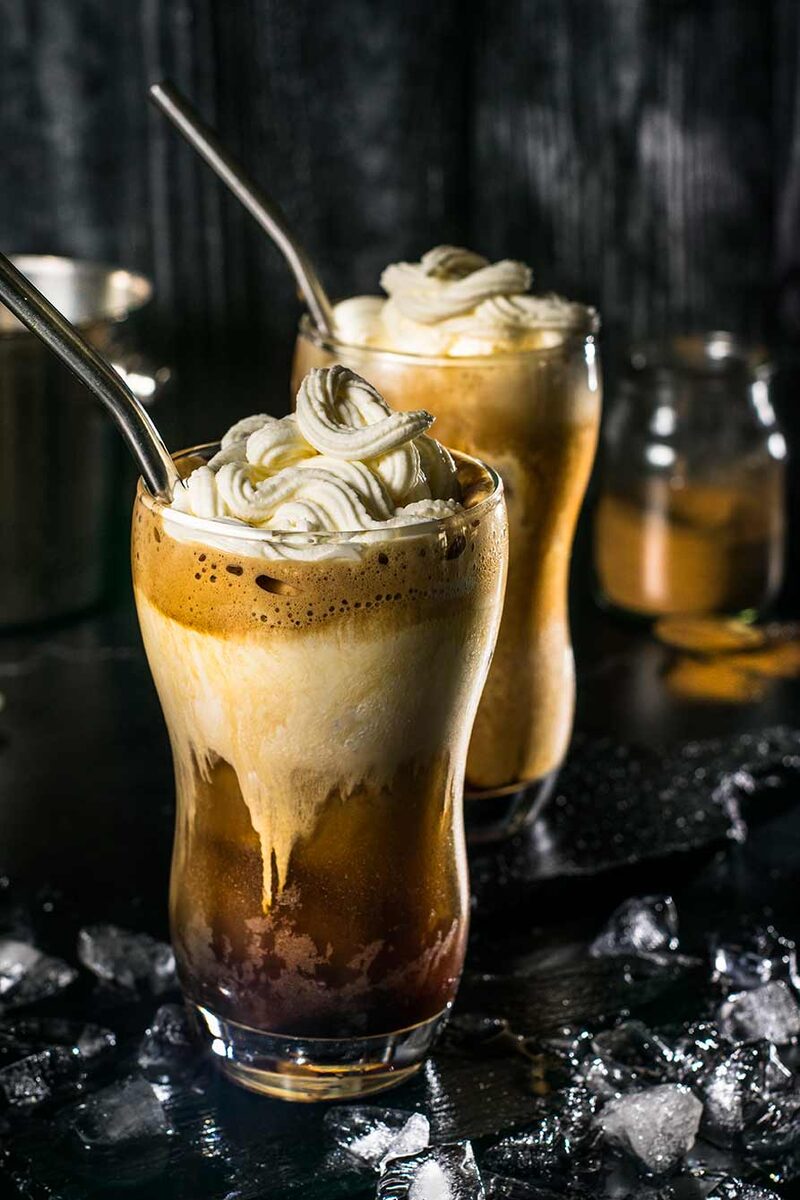 Two iced coffee floats with whipped cream over crushed ice