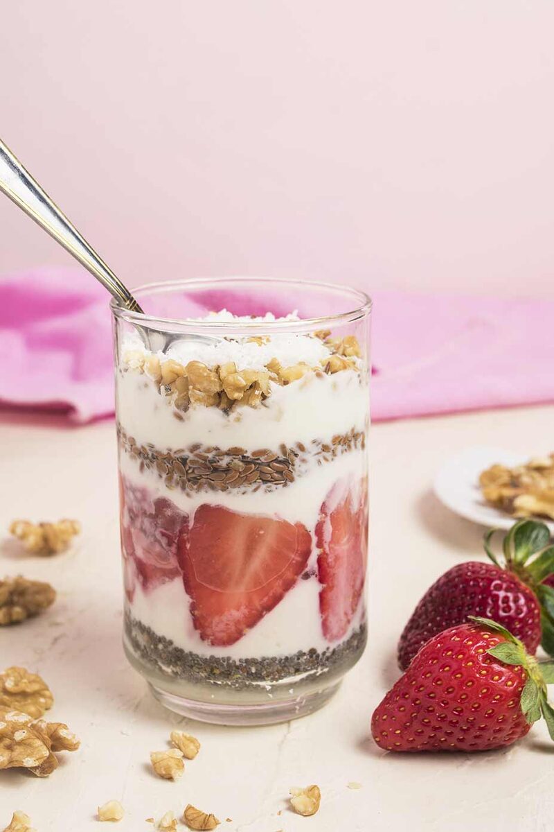 Strawberry yogurt parfait in a glass on a soft pink background
