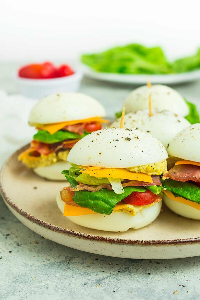 Egg-bun breakfast sliders with bacon and cheese on a plate